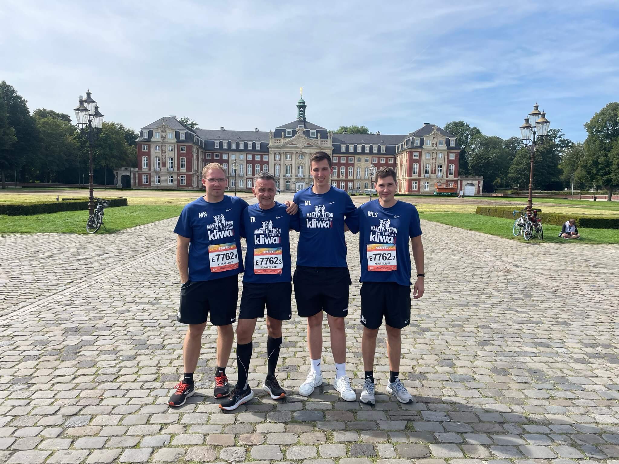 Vier Kliwa Mitarbeiter in Sportkleidung vor einem Schloss.